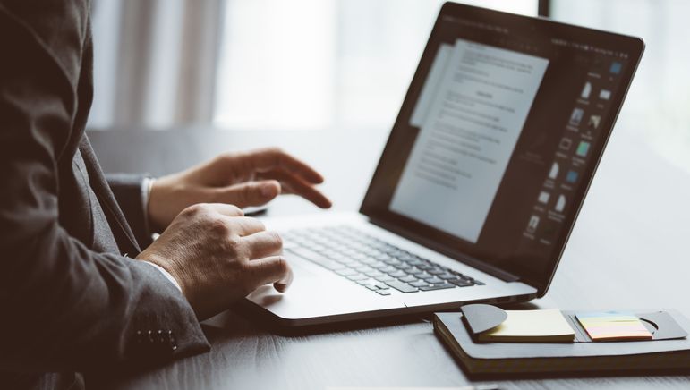 Mann skriver på en bærbar datamaskin